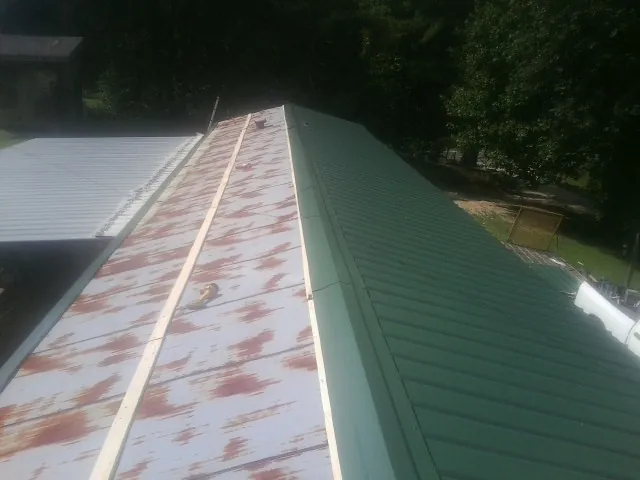 Old rusted panels beside newly installed green metal roofing — Wind Damage Roof Repair by Roofing Brothers in Mount Pleasant